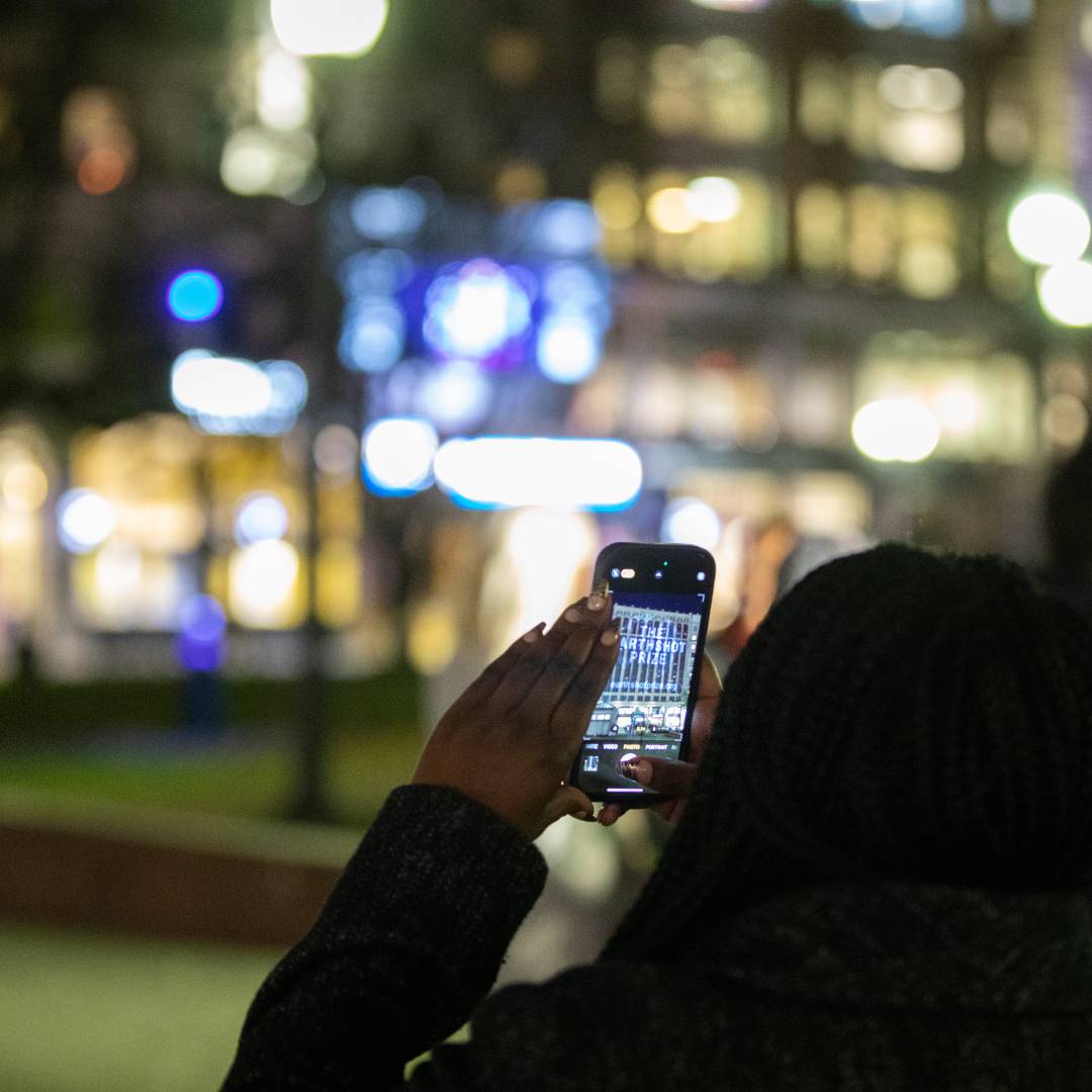 Passers by watch The Earthshot Prize projections on Emerson College building, Boston