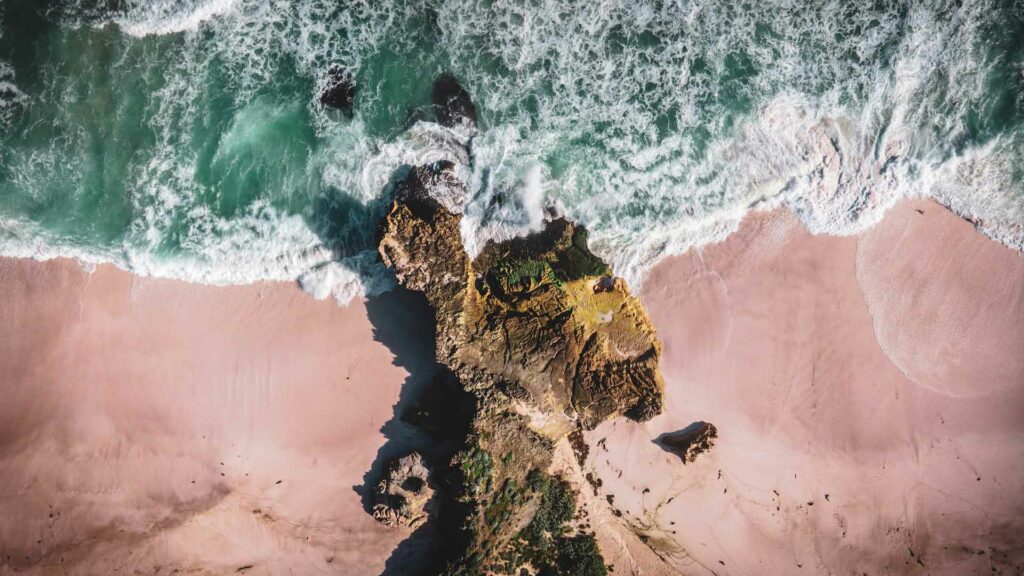 Drone shot of waves breaking on rocky beach